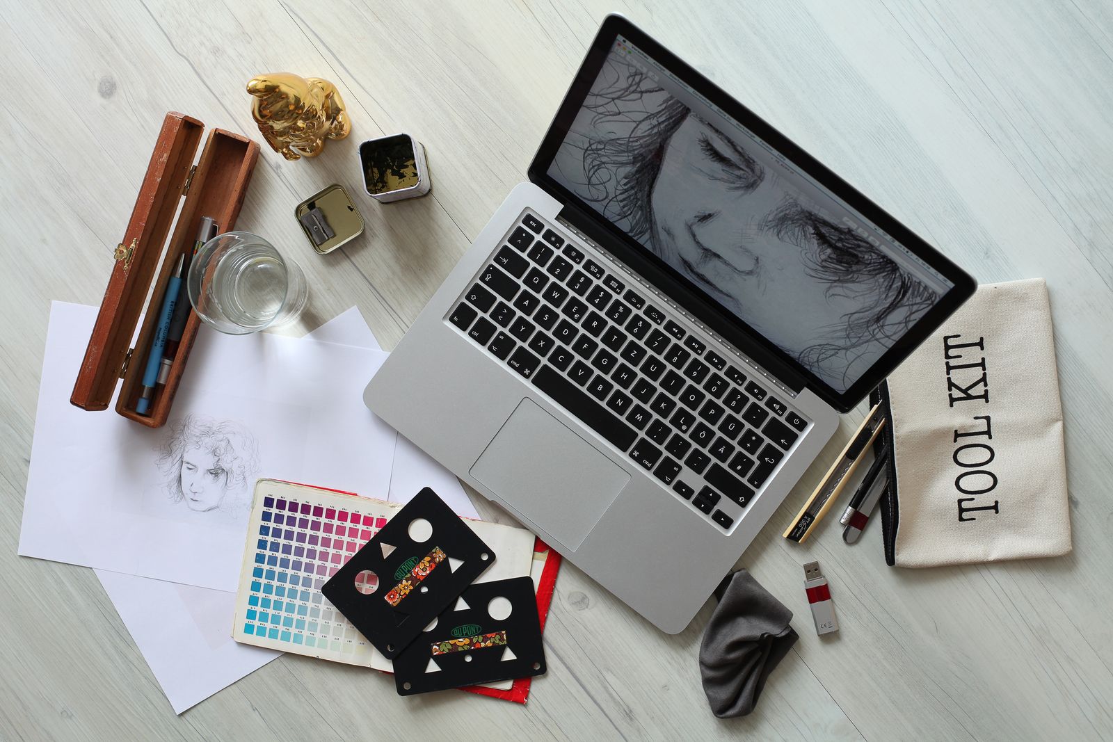 Vista superior de uma mesa de trabalho criativa com laptop, materiais de esboço e paleta de cores