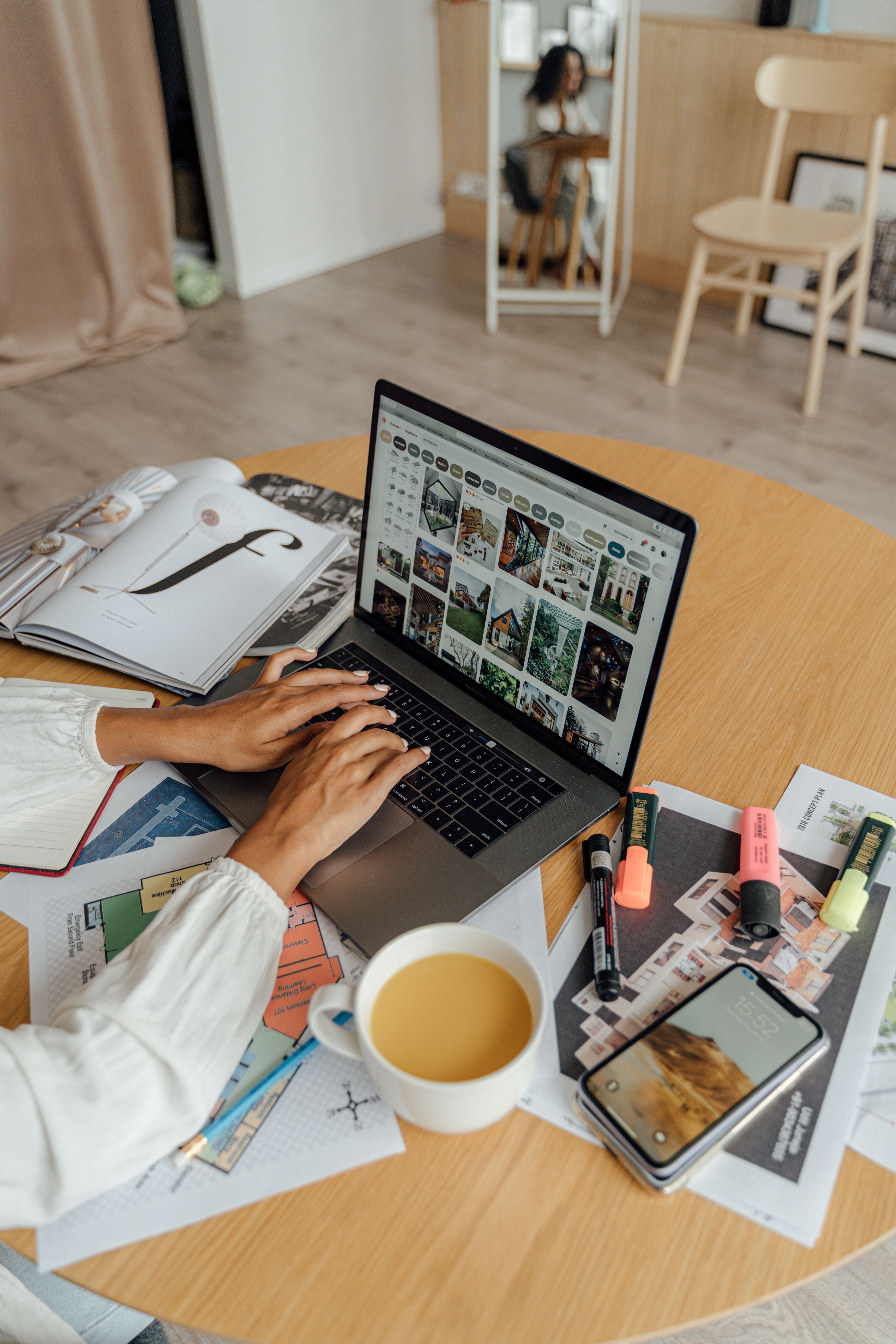 Pessoa trabalhando como freelancer em casa, com notebook, café e revistas em uma mesa de madeira
