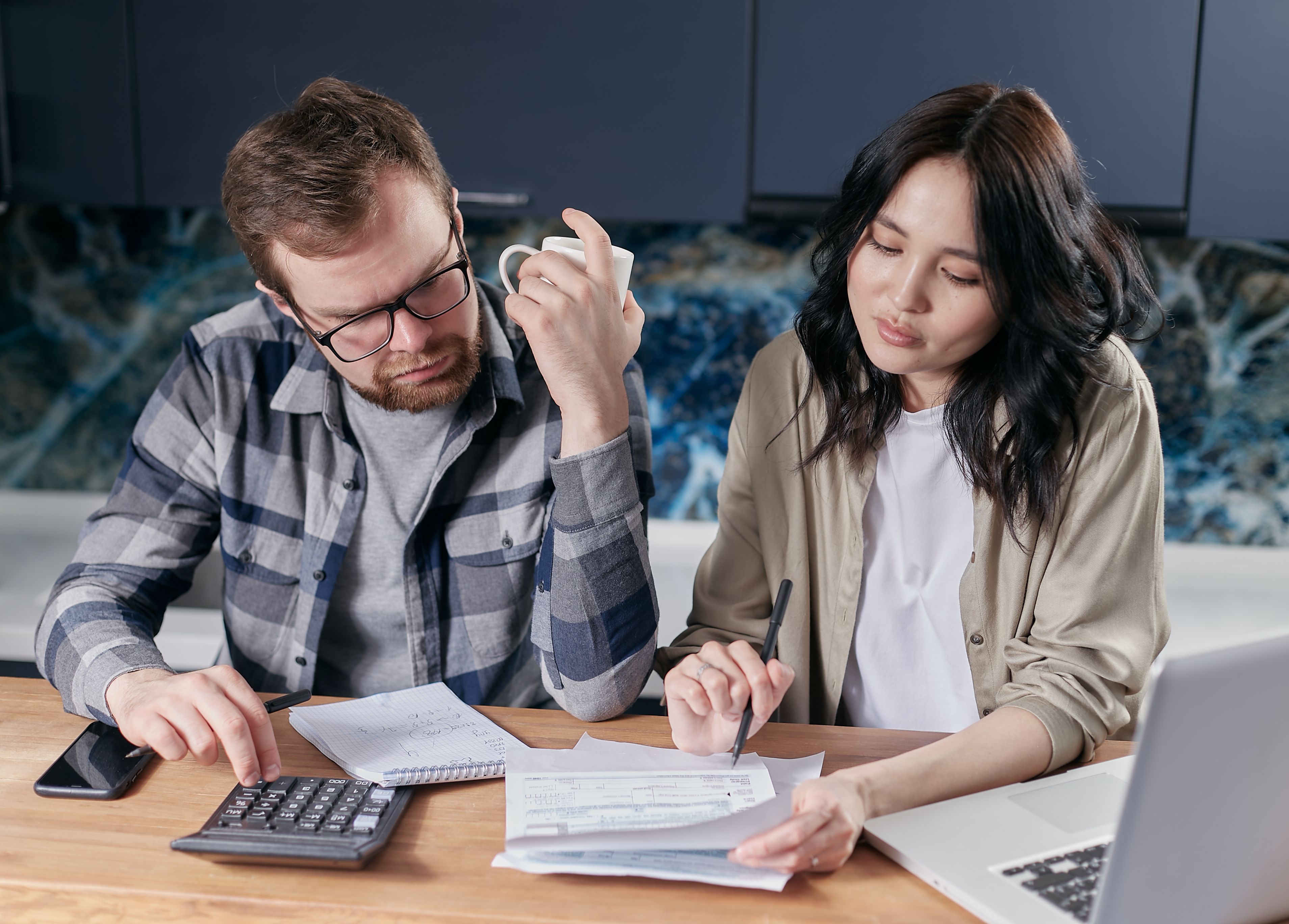 Pessoas revisando orçamento e contas usando calculadora e notebook em uma mesa